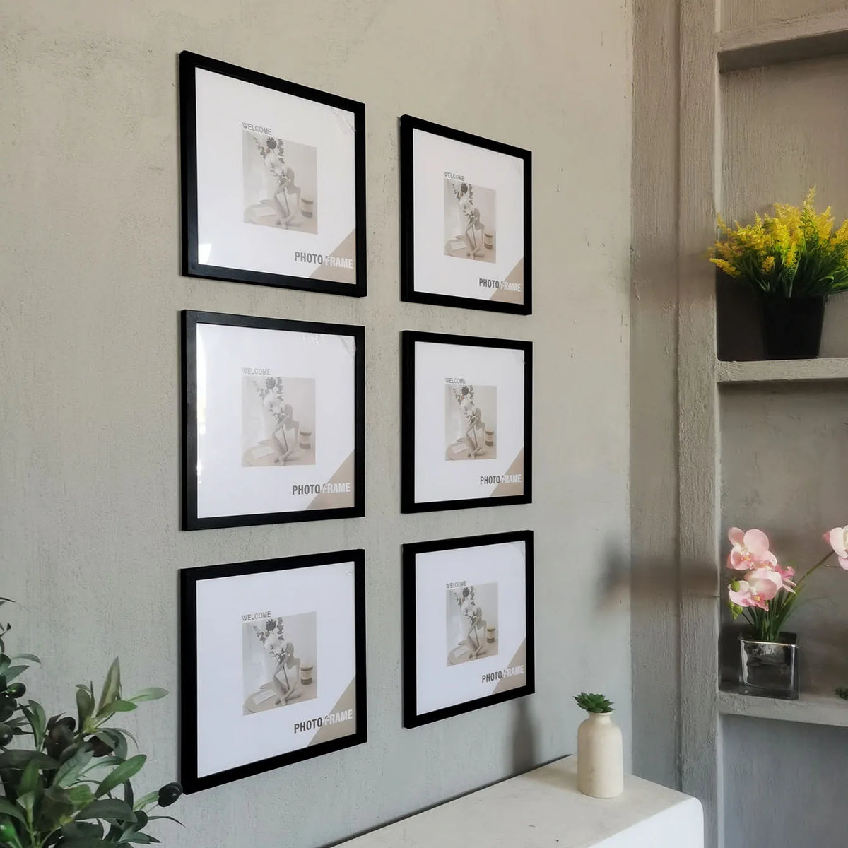 A set of three black photo frames with light wood accents displayed on a gray wall.