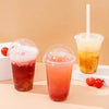 Three plastic cups filled with colorful beverages, including red and orange drinks, served with straws.
