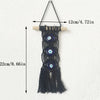 Black macrame wall hanging featuring multiple evil eye pendants on a wooden hanger.