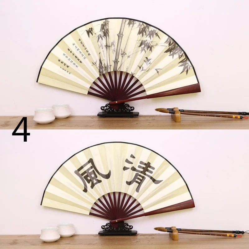 A traditional folding fan with black and cream patterns is displayed on a wooden surface.