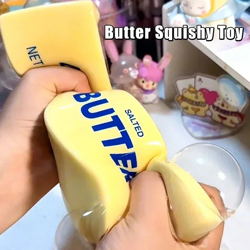 A hand holds a yellow butter squishy toy shaped like a cat paw, demonstrating its texture and form.