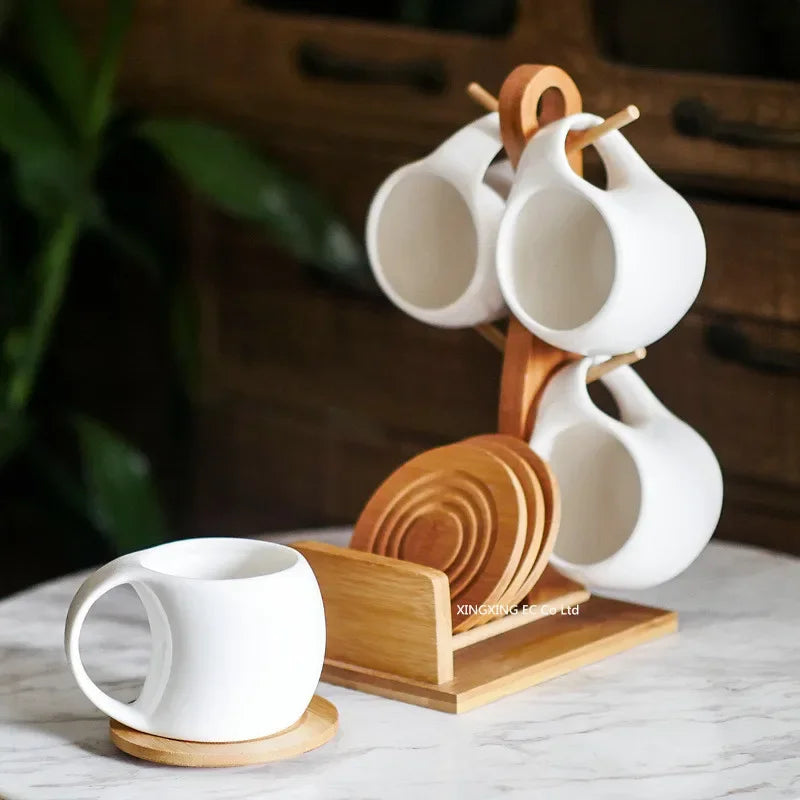 A white ceramic coffee mug set is displayed on a natural bamboo wood stand.