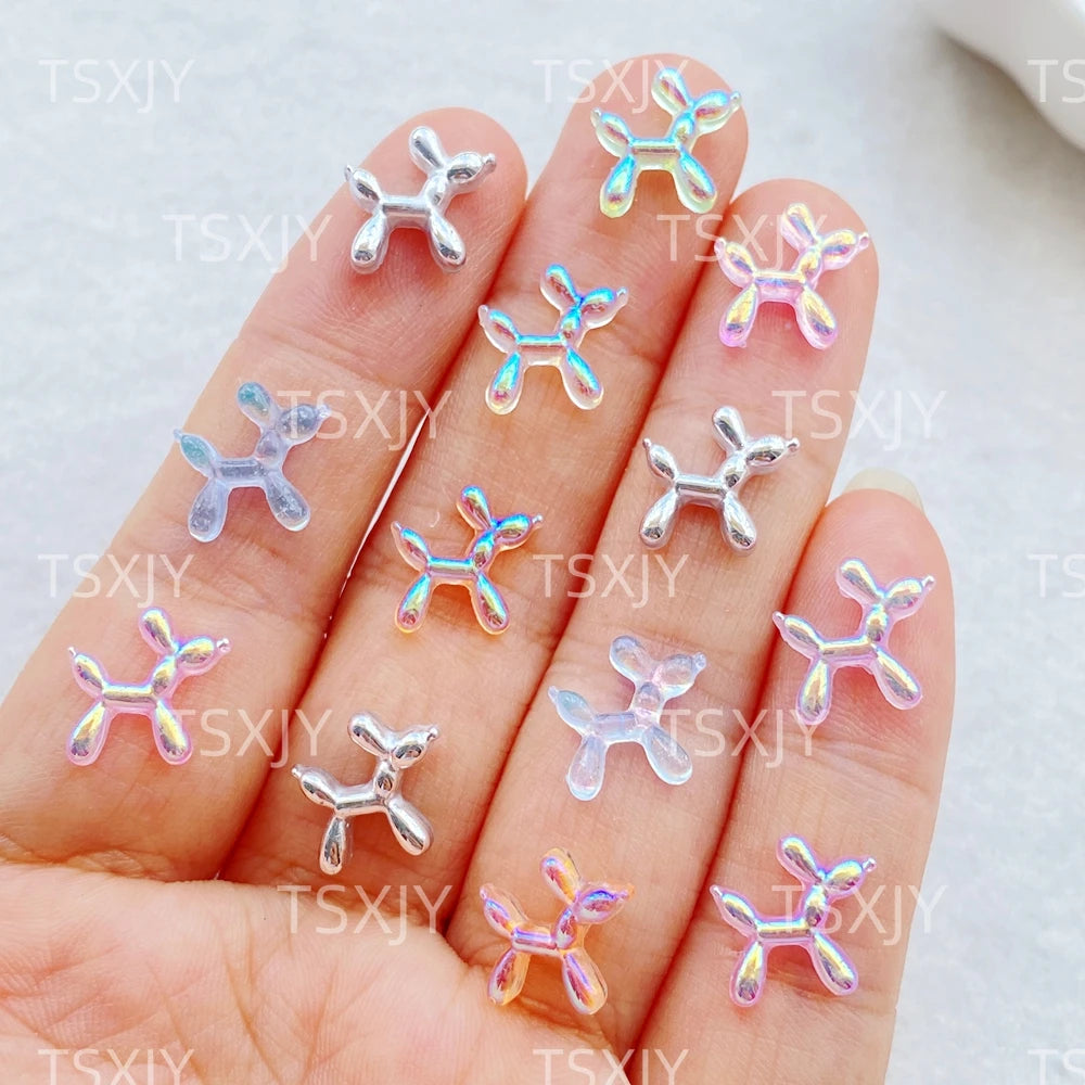 A hand displays various clear and pastel colored balloon puppy nail art charms.