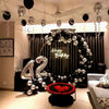 A decorative arch made of silver and black balloons spells out Happy Birthday with a heart design.