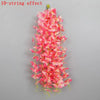 A vertical arrangement of pink and red artificial wisteria flowers forming a long, cascading effect.