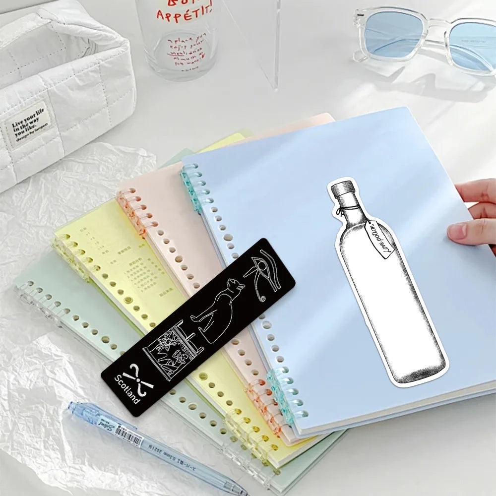 A set of decorative cartoon reading bookmarks in various pastel colors and a white linen pouch are displayed on a light surfa