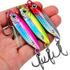 A hand holds a set of colorful metal jig fishing lures with hooks and a storage box.