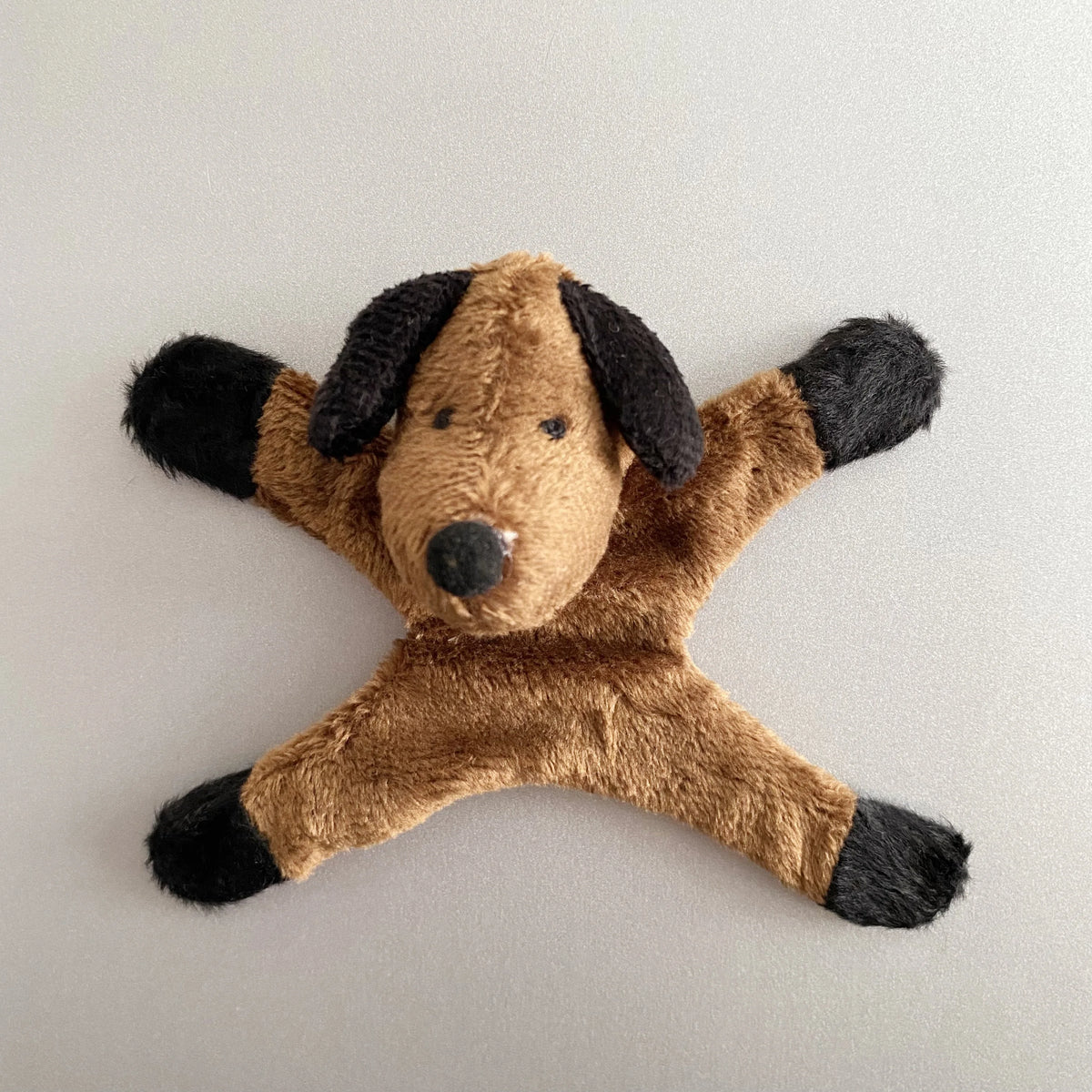 A brown dog plush toy with black markings, used as a fridge magnet design.