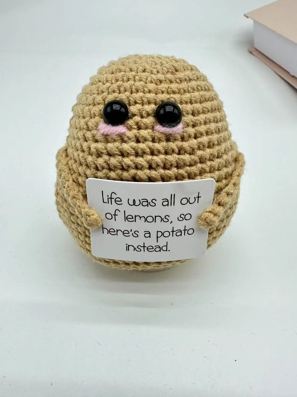 A handmade crochet baseball bat doll with a light brown body and black eyes, featuring a card that reads Life was all out of 