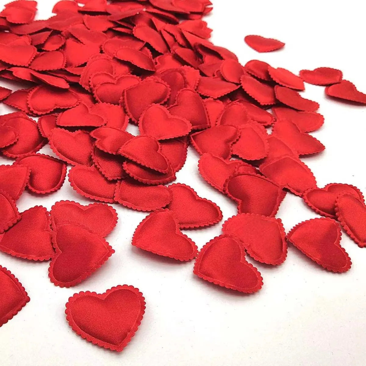 A pile of red fabric heart petals used for weddings and parties.