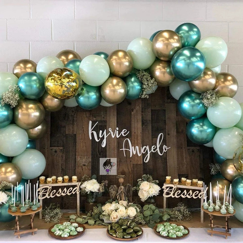 A floral arch made of metallic blue and gold latex balloons decorated with greenery and white flowers.