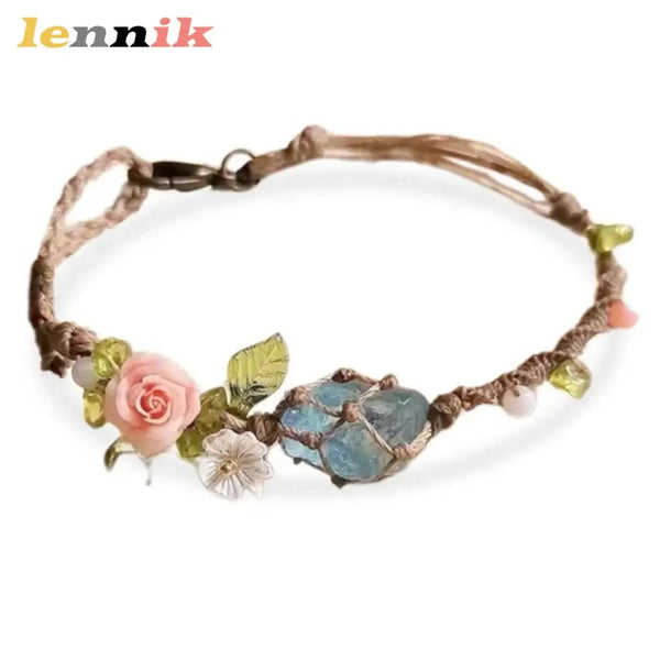 A macrame bracelet featuring raw aquamarine stones and a pink rose accent.