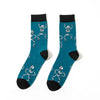 A pair of teal crew socks featuring repeating white skull and alien prints on a black background.