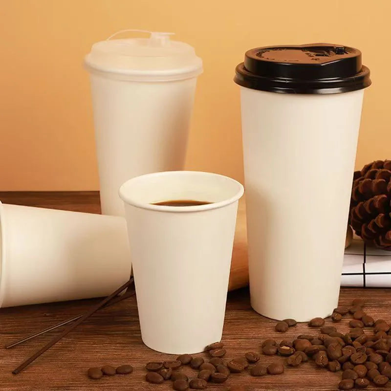 A set of disposable paper coffee cups, including a large cup with a lid and smaller cups, resting on a wooden surface.
