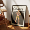 A framed poster of Charles Oliveira featuring a portrait in a fighting stance, displayed on a wooden surface.