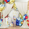 A white draped backdrop with gold balloons and blue/red balloons for a baby celebration