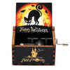 A carved wooden music box featuring a Halloween themed scene with a black cat silhouette against an orange sun background.