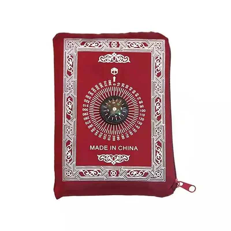 A red portable travel prayer mat with a compass design, featuring intricate patterns and a central circular motif.