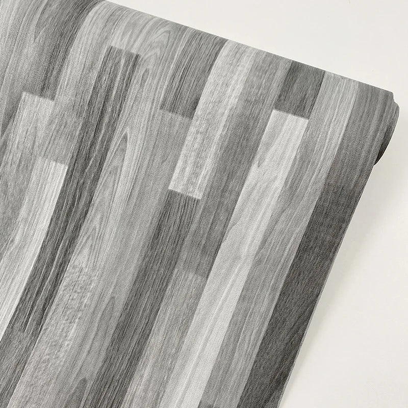 Close-up of realistic wood grain floor stickers showing vertical stripes in shades of gray and white.