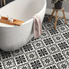 A white bathtub is positioned above a floor covered with black and white Moroccan pattern stickers.