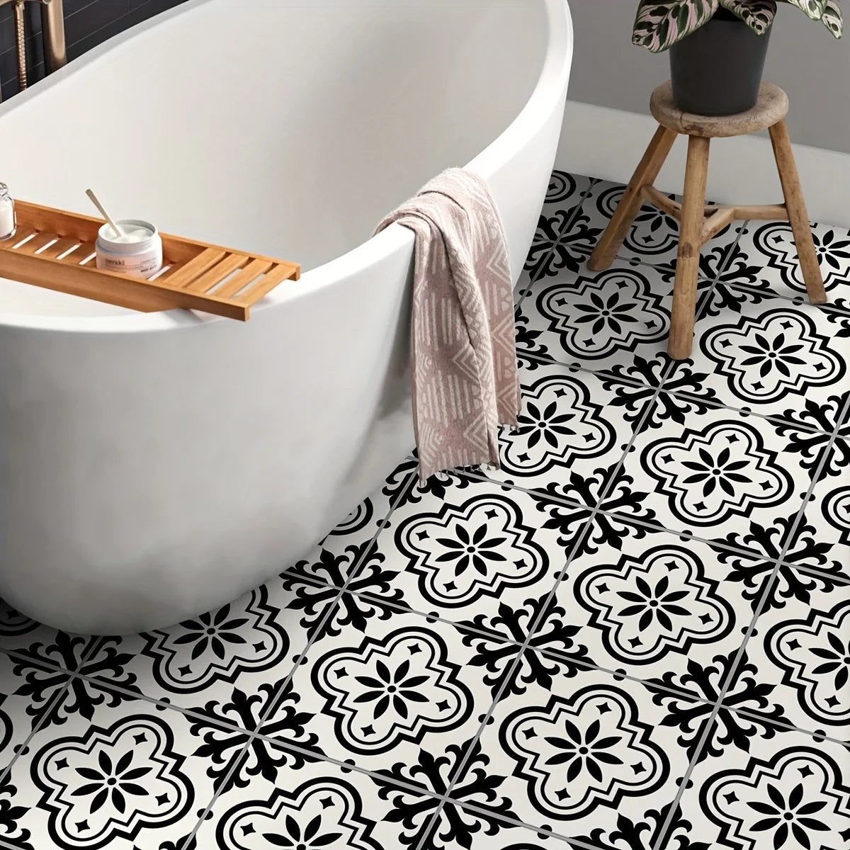 A white bathtub is positioned above a floor covered with black and white Moroccan pattern stickers.