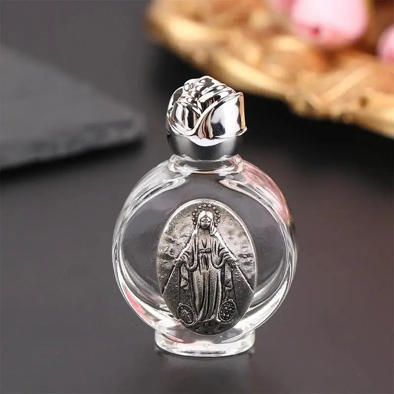 A clear glass bottle containing a religious sculpture of Jesus in an oval frame with a silver cap.