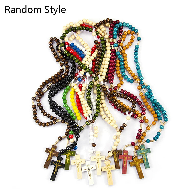 A tangled necklace of wooden rosary beads and crucifixes in various colors like red, green, yellow, and brown.
