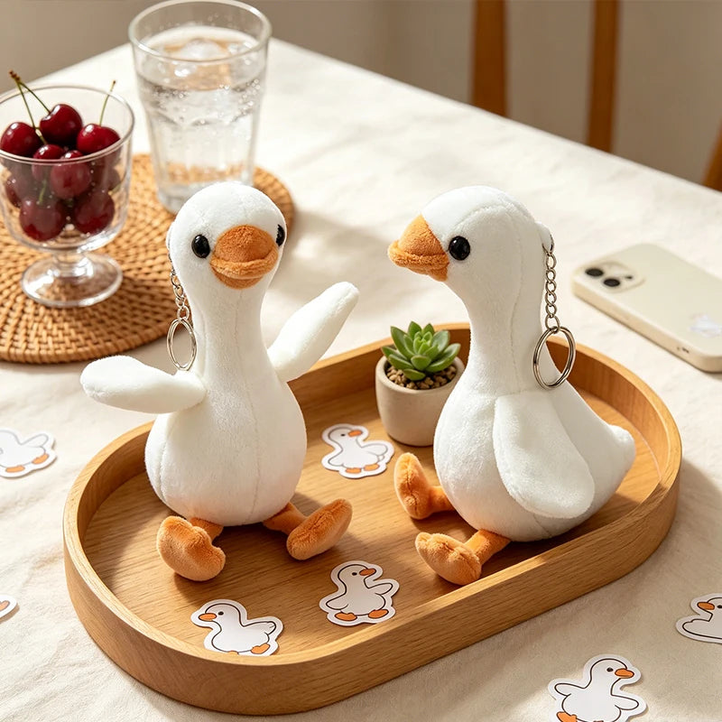 A white duck plush toy is displayed on a wooden tray with various duck-shaped stickers and a glass of water.