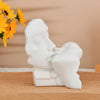 White resin sculpture of an abstract kissing couple against a light background.