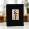 A black linen photo album with a display window showing a photo of a couple embracing.