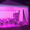 A tent decorated with pink fairy curtain string lights illuminating the interior.