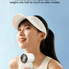 A young woman is using a white portable rechargeable mini handheld fan for cooling.