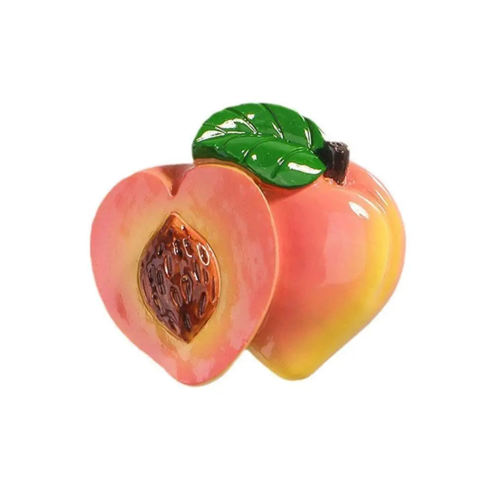A glossy pink and yellow apple with a green leaf, used as a fridge magnet.