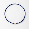 A dark blue handmade string bracelet with a gold plated clasp.