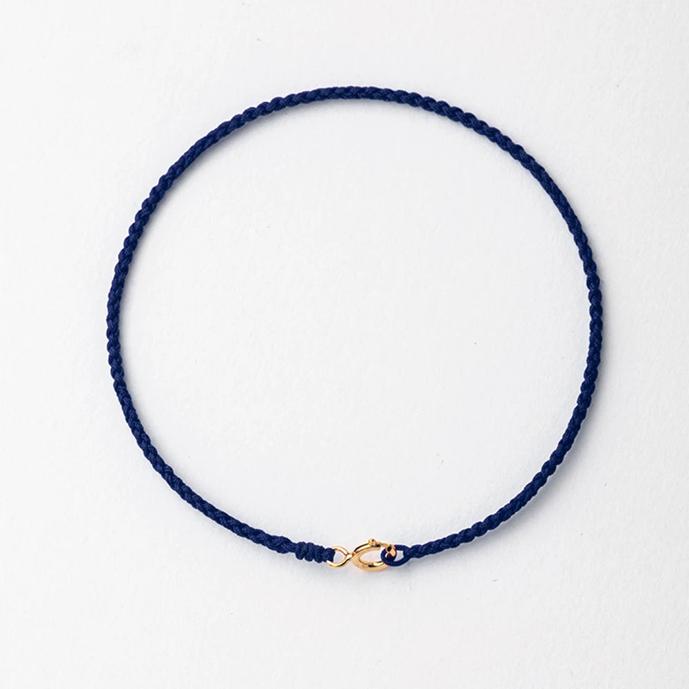 A dark blue handmade string bracelet with a gold plated clasp.