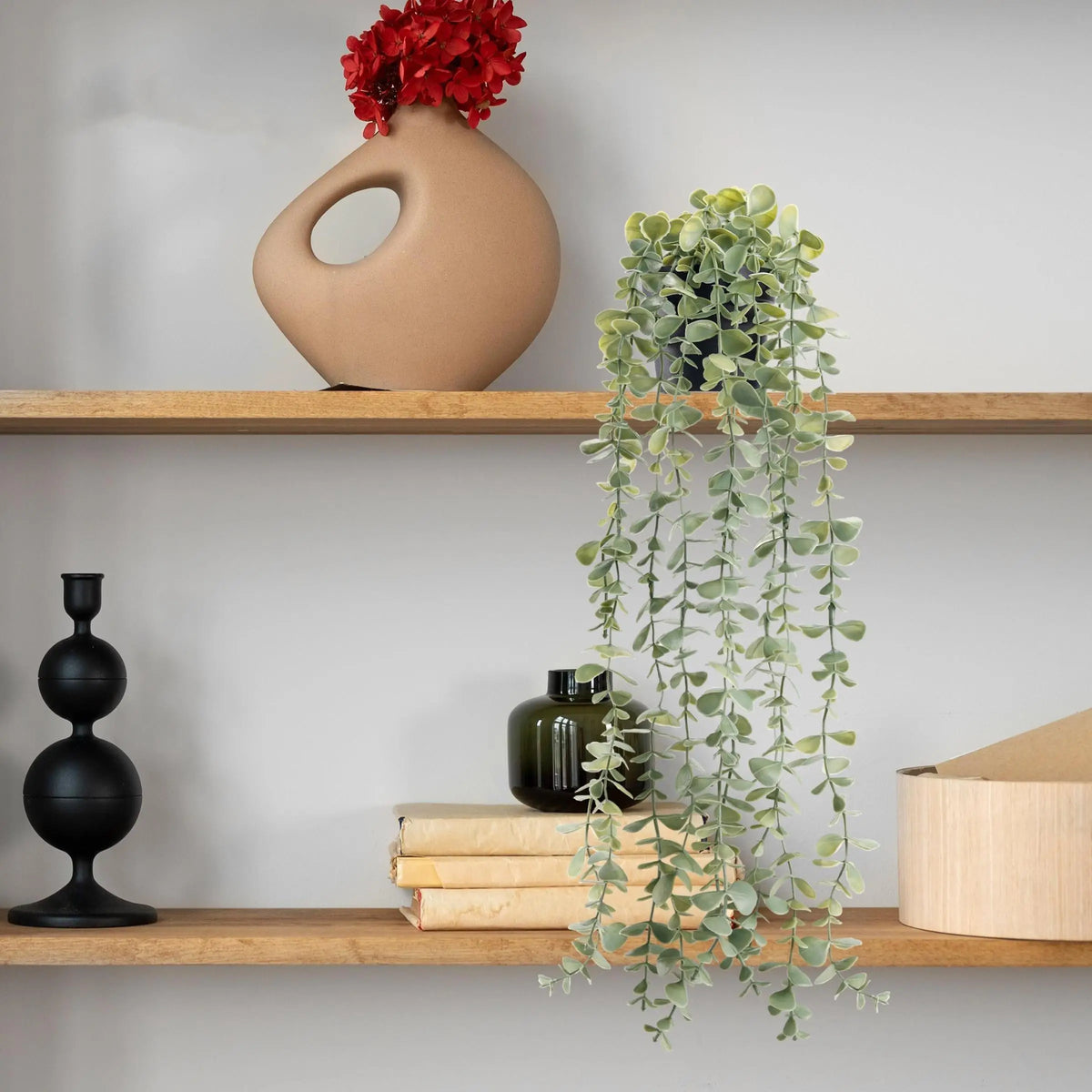 Plantes d'eucalyptus artificielles suspendues avec du feuillage vert sur une étagère en bois.