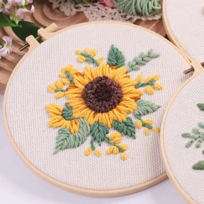 Punch needle embroidery kit featuring a sunflower design on a beige cloth with wooden tools