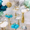 A collection of clear and iridescent bubble balloons in shades of blue, green, and gold for party decoration.