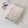 A silver leather photo album with a pink ribbon closure and star embellishments is displayed on a white surface.