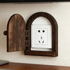A close-up of a decorative wooden outlet cover mounted on a white wall.