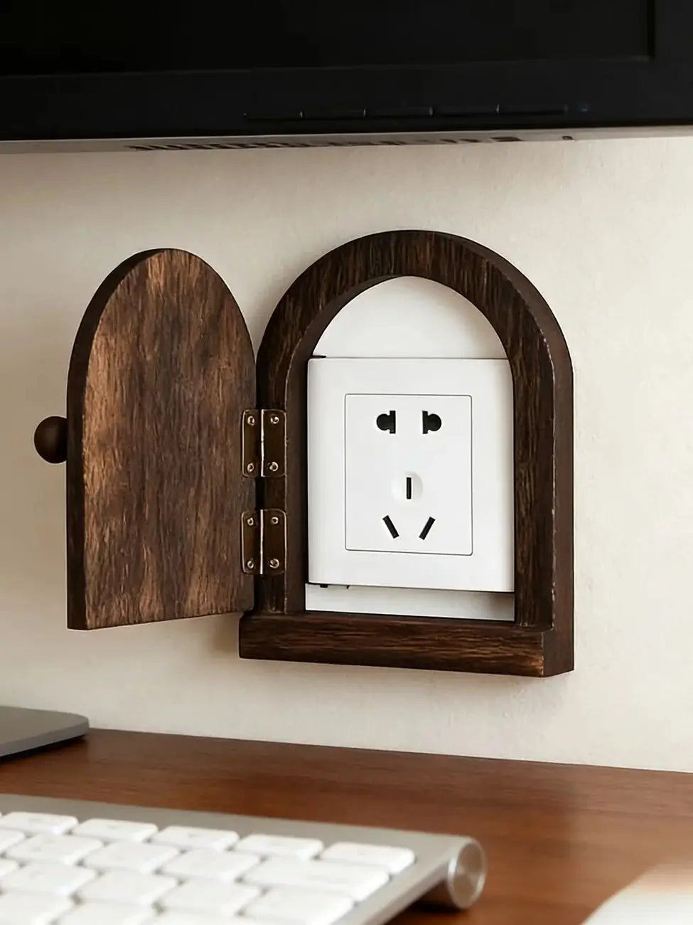 A close-up of a decorative wooden outlet cover mounted on a white wall.