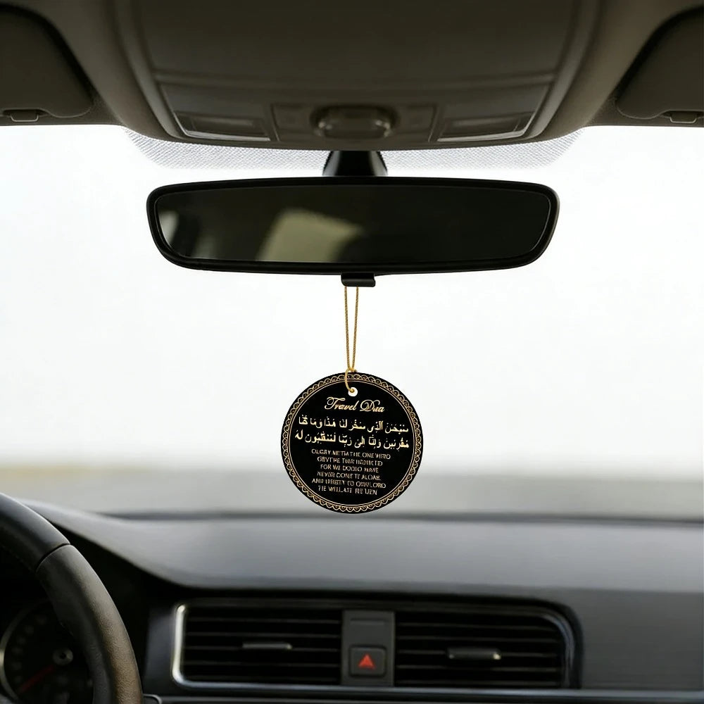 A black prayer tag hangs from the rearview mirror inside a car, featuring Arabic and English text.