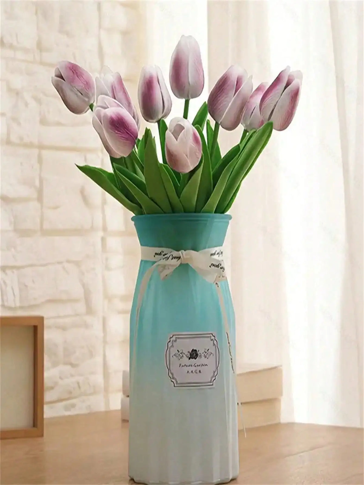 A bouquet of six artificial purple and pink tulips in a light blue ceramic vase