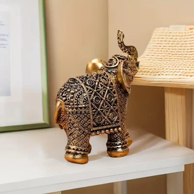 A vintage resin elephant ornament with intricate gold detailing sits on a white shelf.