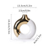 A white and gold ceramic flower vase with a curved, open shape.
