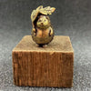 A brass figurine of a hedgehog with a leaf and flower detail, resting on a wooden block.
