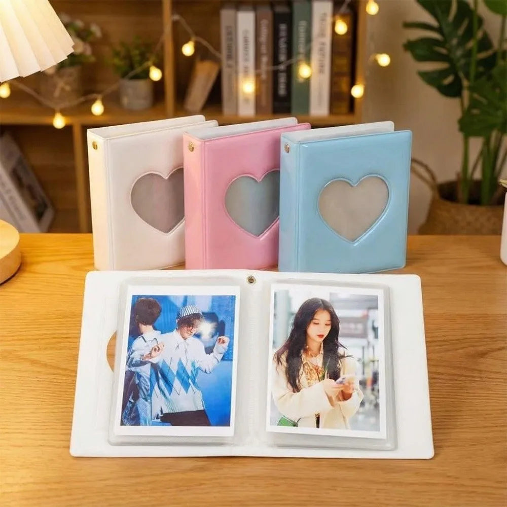 A set of four heart-shaped photo albums in white, pink, and blue, displayed on a wooden table.