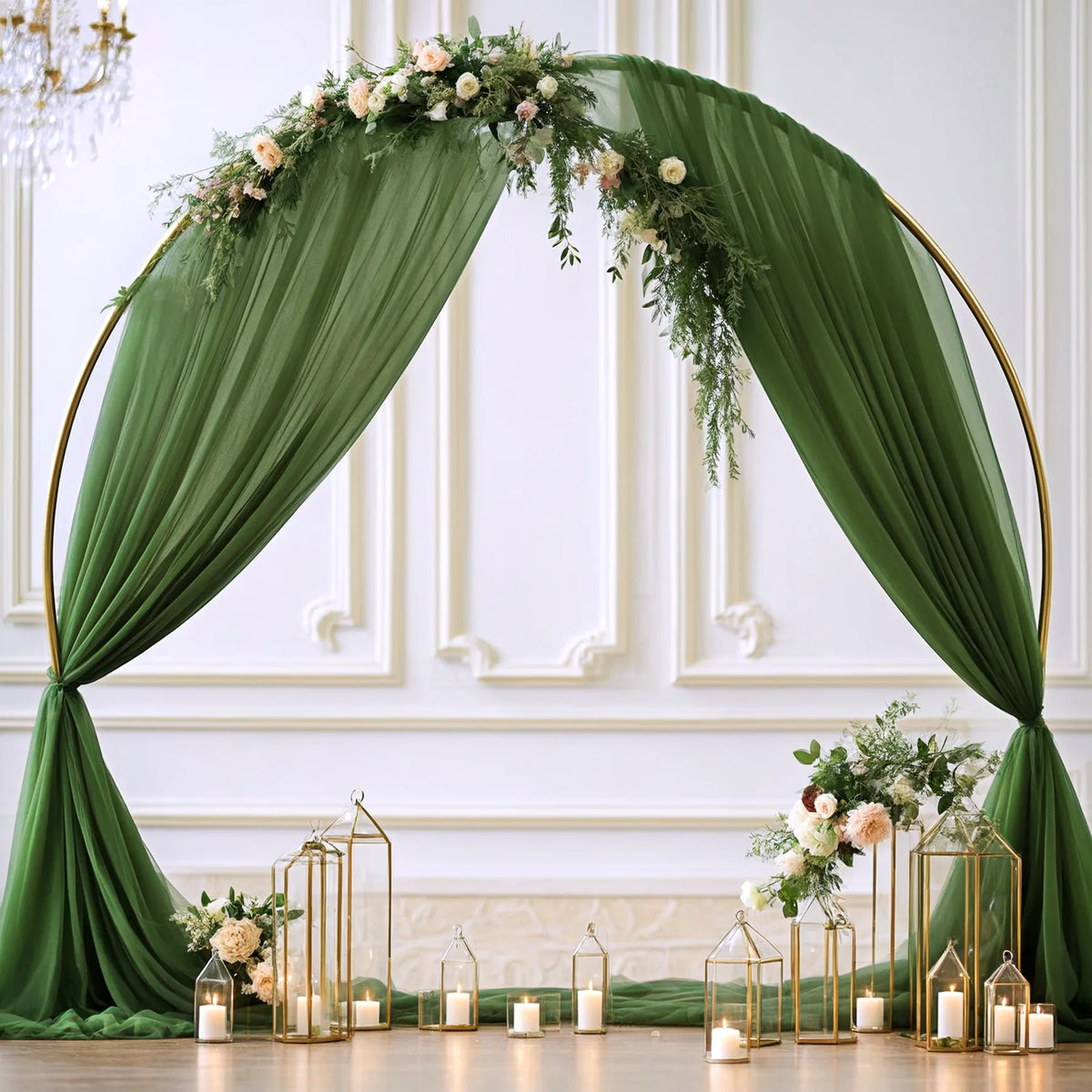 Elegant green chiffon arch drapes framing a white wall with floral greenery and gold accents