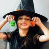 A smiling girl holds up two miniature pumpkin Halloween buckets for treats and decor.