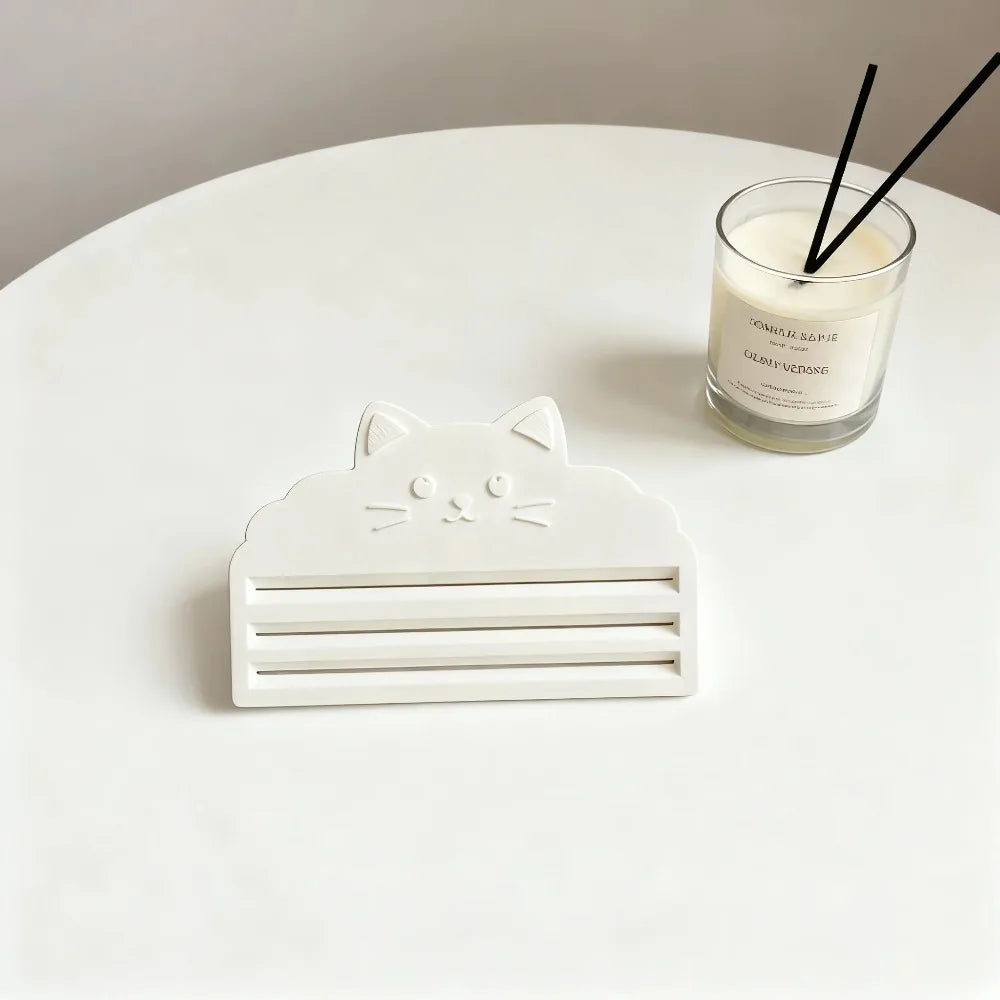 A white cat food bag squeezer tool is placed on a white table next to a glass of milk.